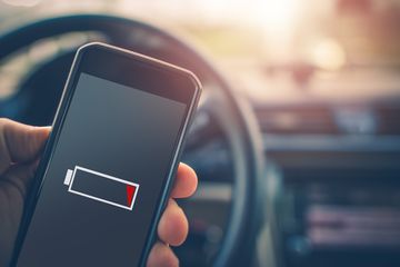 Une main tenant un smartphone dans une voiture